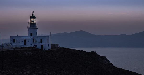 Armenistis lighthouse standing on the rocky headland of northwest Mykonos