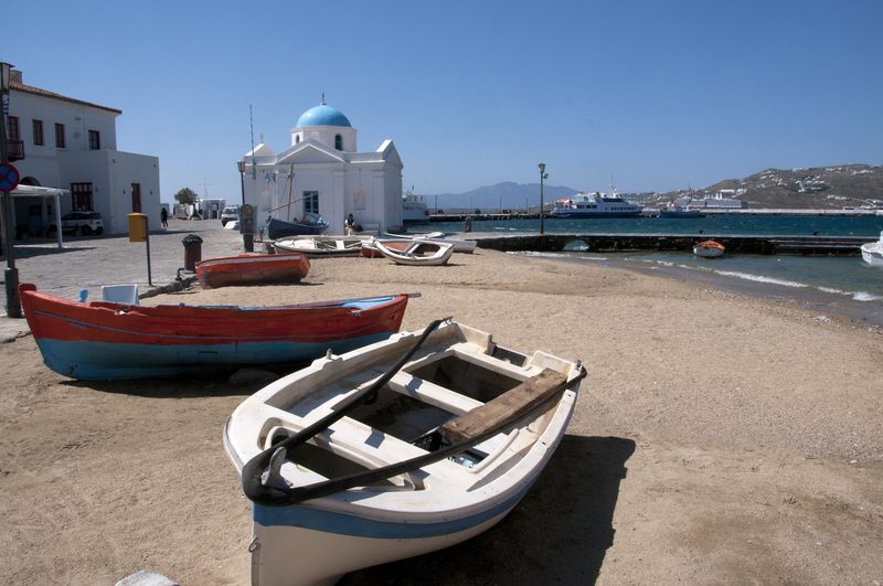 A serene beach with clear waters and rocky cliffs on Mykonos' North Coast.
