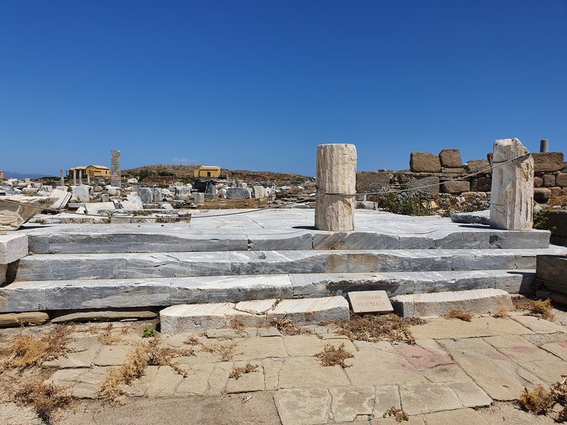 Marble ruins and an ancient entrance marker scattered across the Delos archaeological site