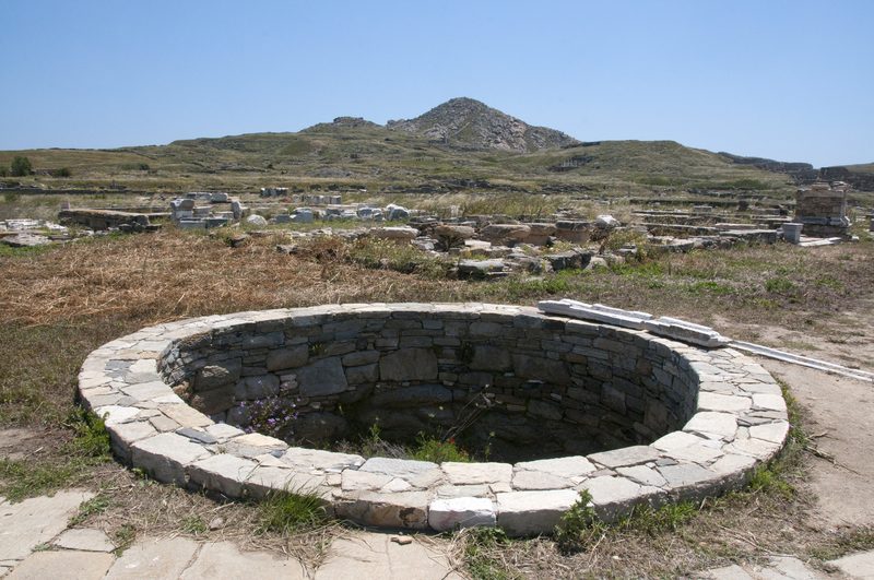 A serene beach with ancient ruins in the background on Delos Island, Greece.