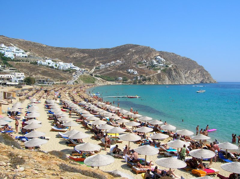 A serene view of Elia Beach on the Greek island of Mykonos, featuring clear blue waters and sandy shoreline.