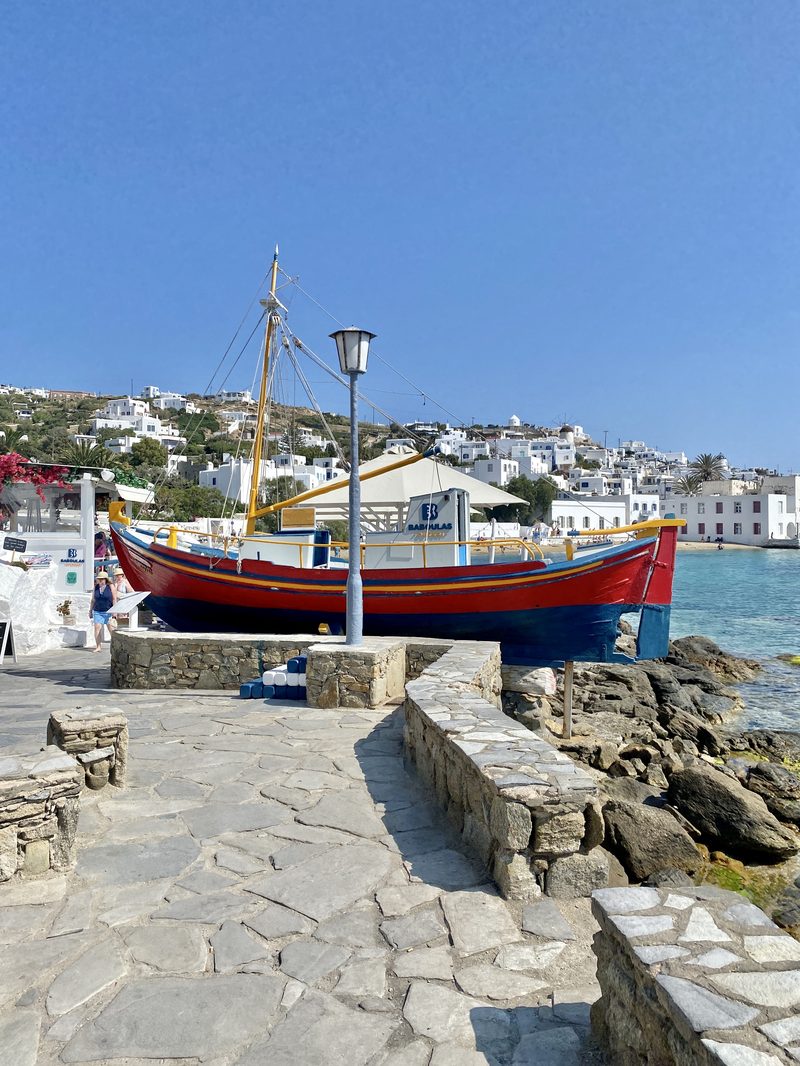 A picturesque coastal scene with a boat anchored near a rocky shore in Mykonos.