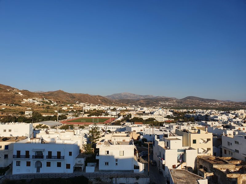 Whitewashed rooftops of Naxos Chora spreading down the hillside, with the island's mountains rising behind