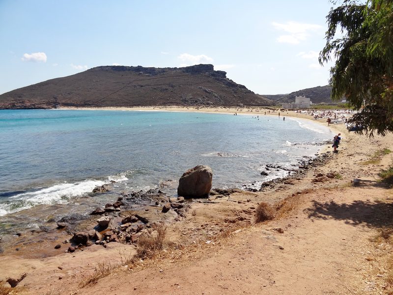 A serene beach scene at Panormos Beach on Mykonos, Greece, with clear waters and sandy shores.