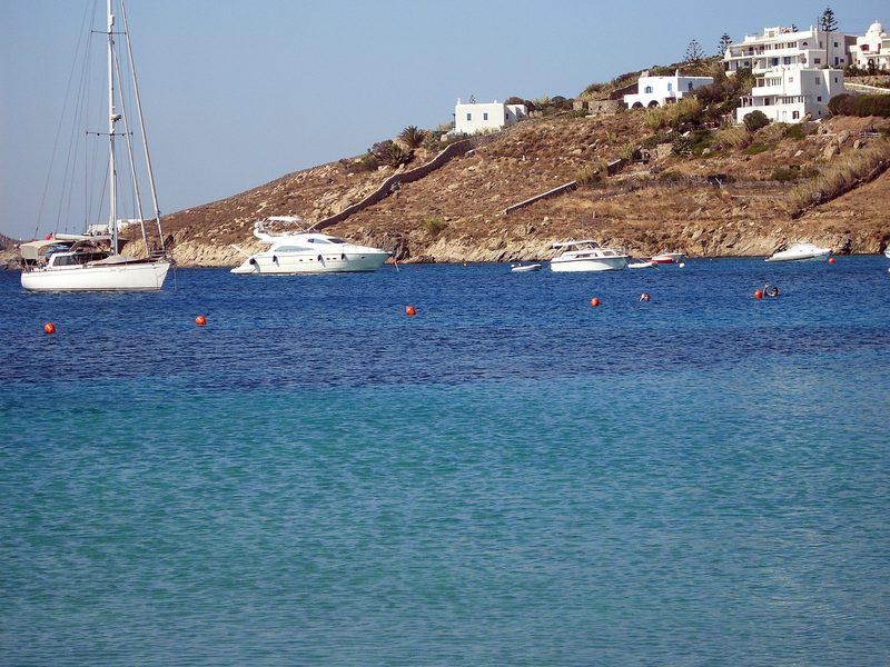 A serene beach scene at Psarou Beach, Mykonos, with clear waters and a few sunbathers.